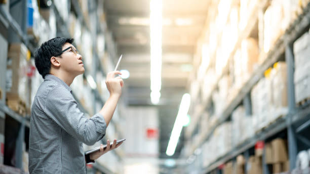 Manager analyzing warehouse inventory with tablet for data-driven demand forecasting.