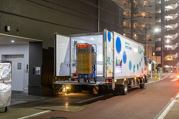 Refrigerated truck at night unloading produce crates during a cross-docking operation.