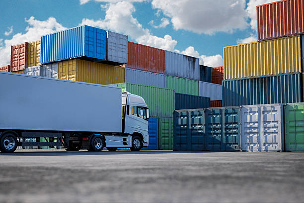 Truck parked near stacked shipping containers at a logistics yard.