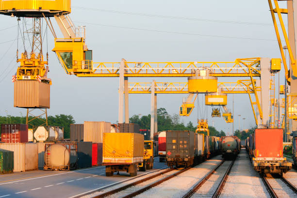 Freight terminal with trucks, trains, and cranes moving shipping containers.