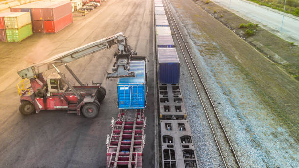Loader placing shipping containers onto a freight train at a rail terminal.