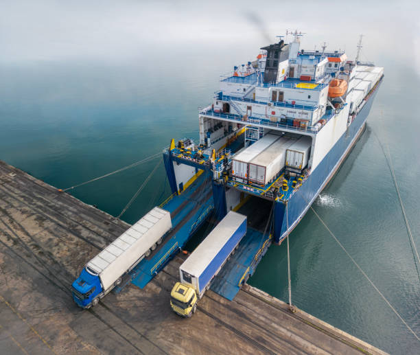 Trucks loading onto a cargo ship at a port terminal. 