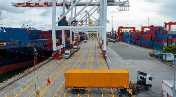 Shipping containers and trucks at a busy port terminal with large cranes.