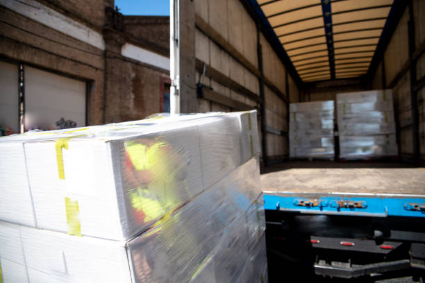 Shrink-wrapped pallet being loaded into a truck at a warehouse dock.