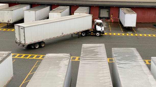 Truck moving a trailer at a busy warehouse loading dock.