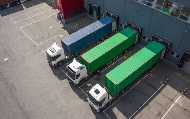 Aerial view of semi-trucks with cargo containers at a warehouse loading dock.