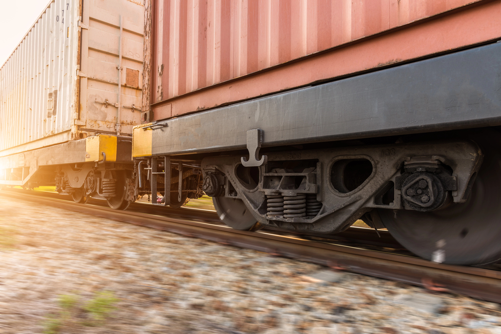 Railway siding with freight cars positioned beside loading equipment near a docked cargo ship.