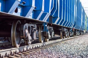 Freight car parked along a railway siding beside an industrial warehouse.